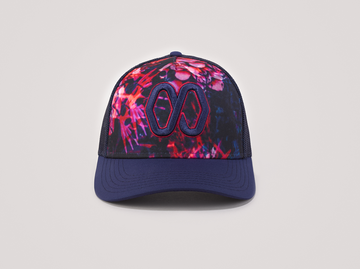 Ponytail baseball hat with blue and pink print. Mesh trucker style. Rear opening with cross tie. Front view.